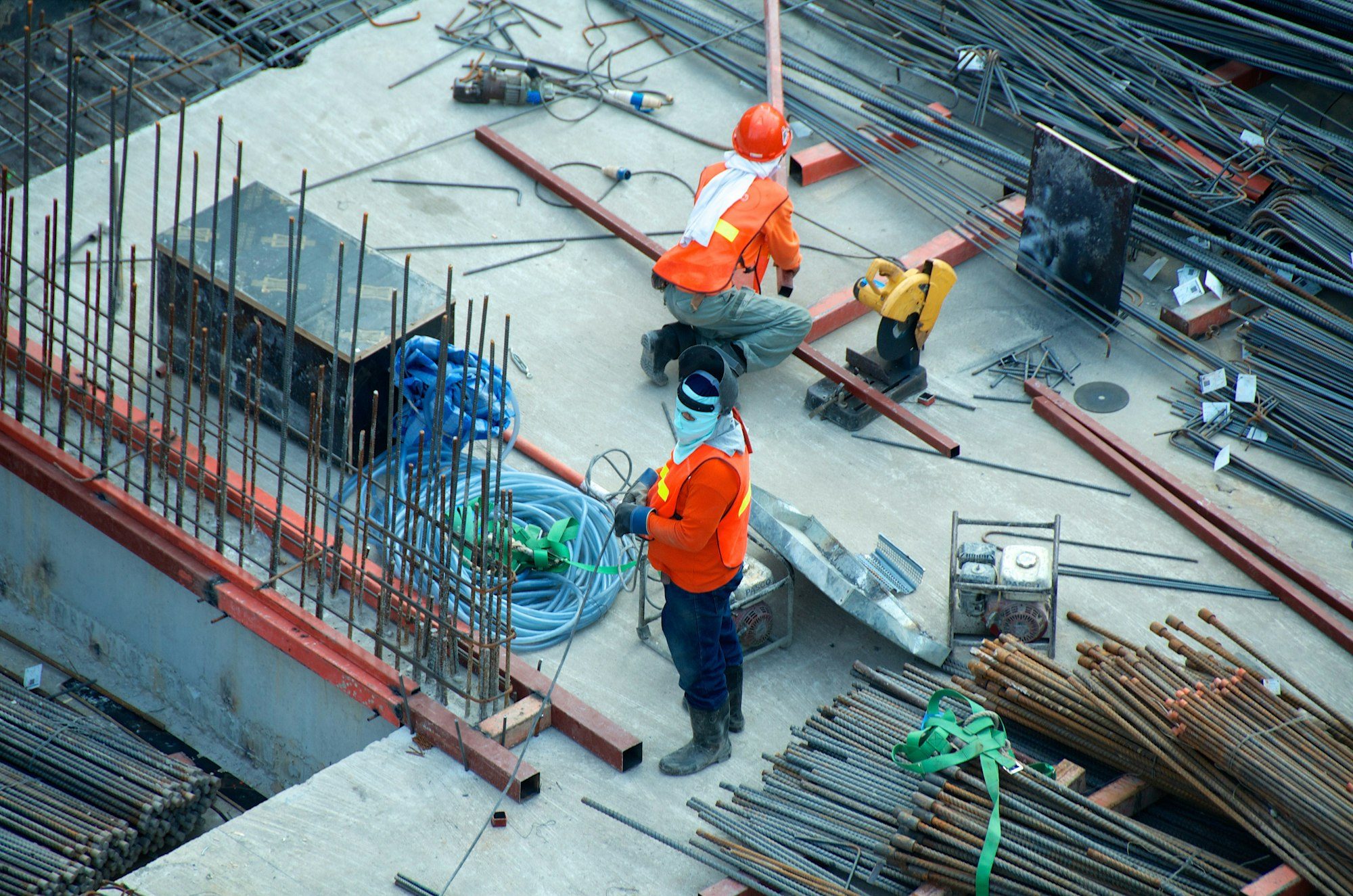 Workers on a construction site among stacks of rebar