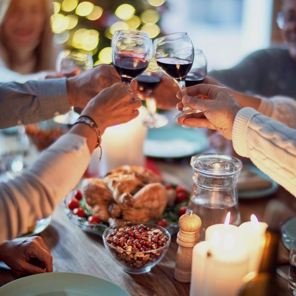 Friends raising glasses of red wine over a candlelit dinner table