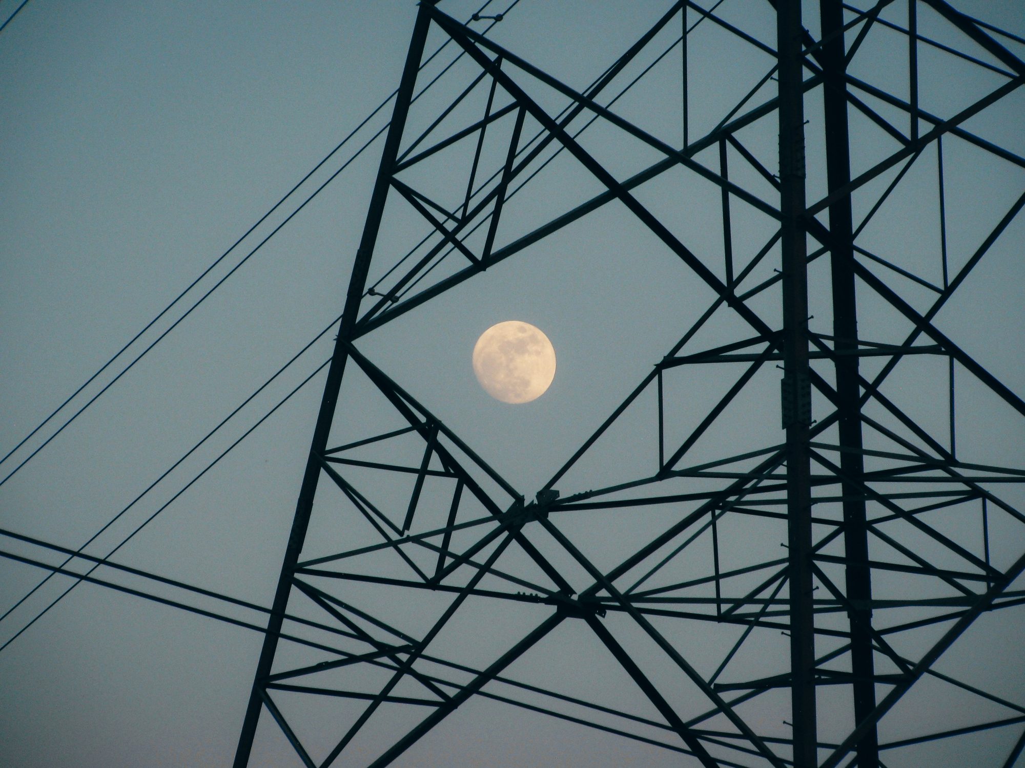 Transmission towers with the moon behind them